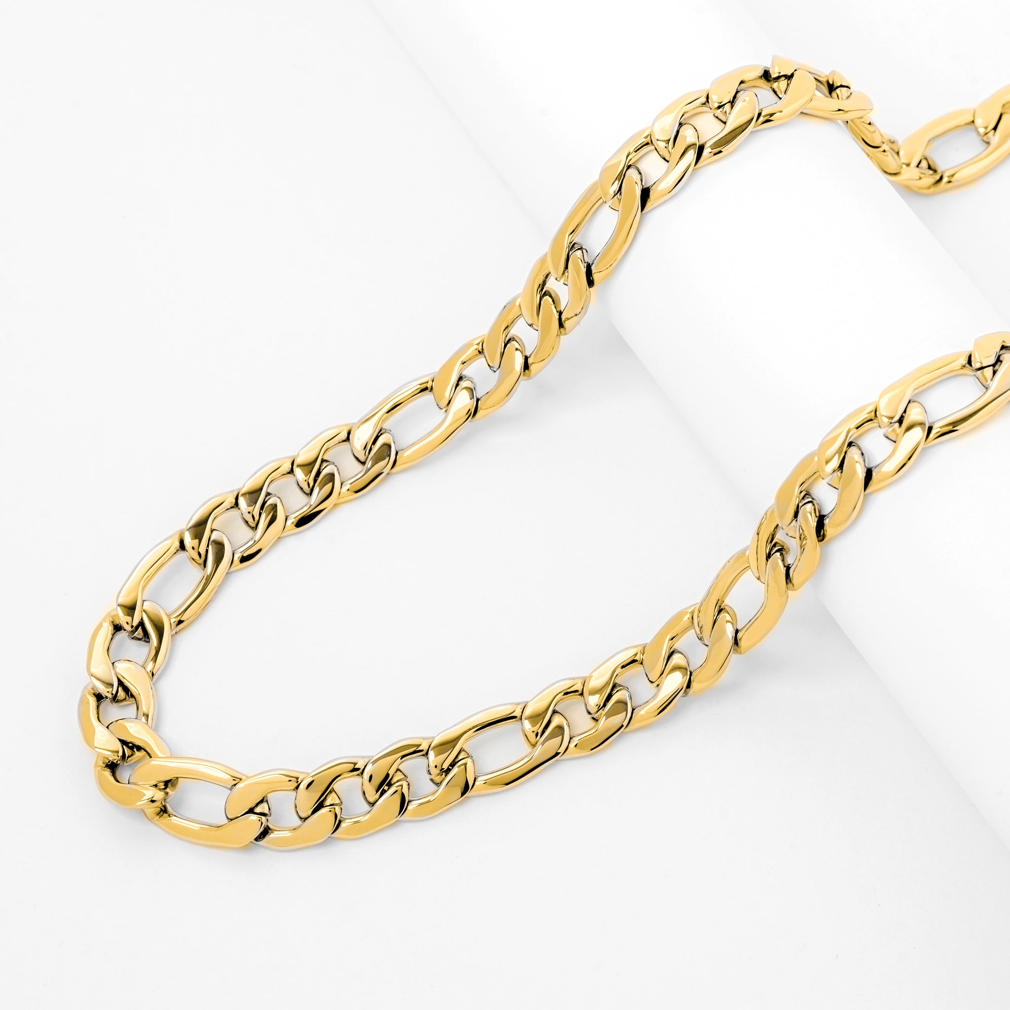 Gold figaro chain displayed on white surface showing chain length and link pattern