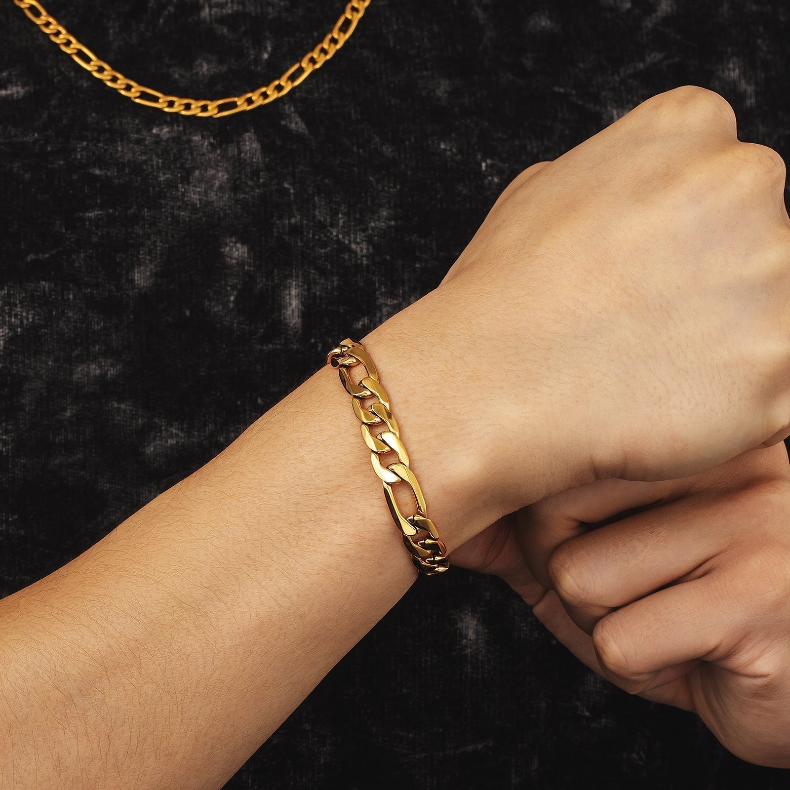 Gold figaro chain bracelet worn on wrist, styled with matching chain necklace