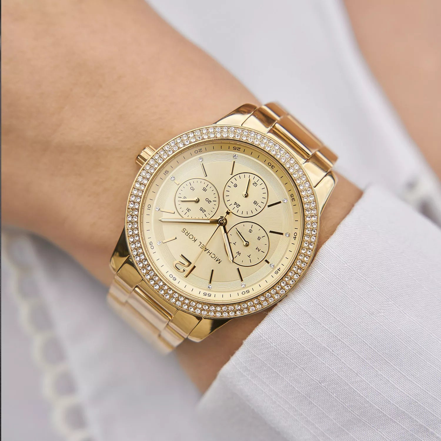 Michael Kors Oversized Tibby gold chronograph watch worn on wrist with crystal bezel detail