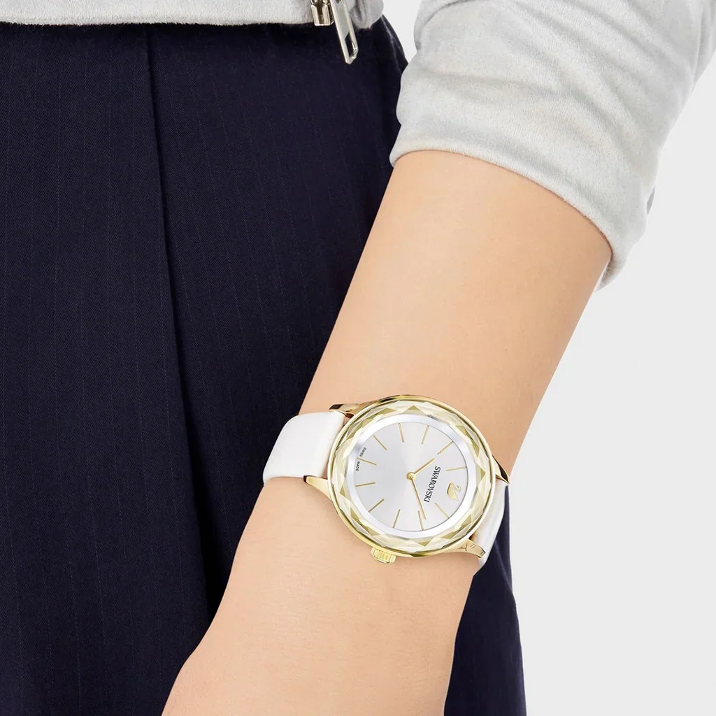 Swarovski Octea Nova quartz watch worn on wrist with white leather strap and gold-tone case