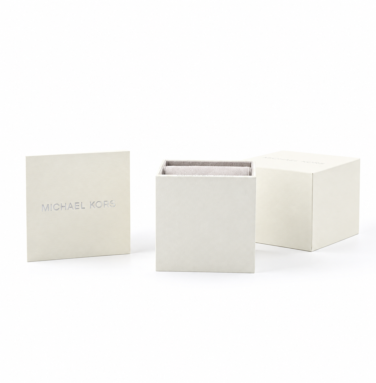 Michael Kors jewelry box set in a warm off-white textured material, featuring a closed lid with the brand name, an open box, and a second closed box on a clean white background.