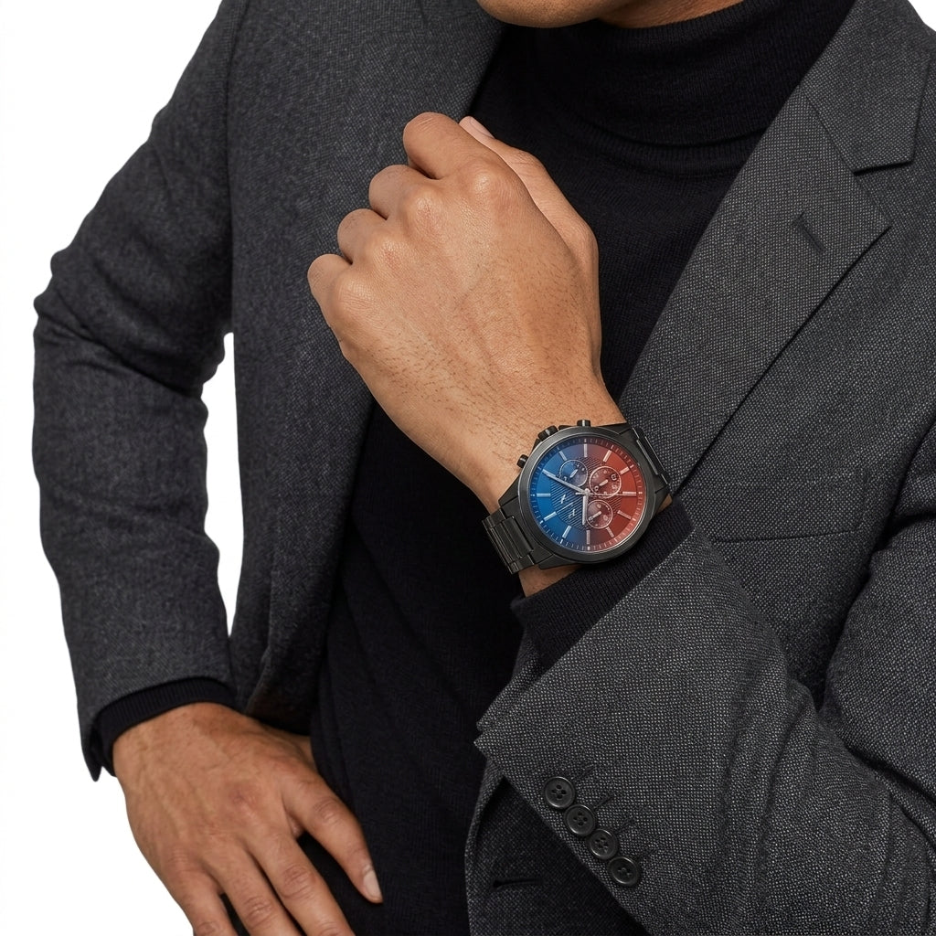 A close-up of a man wearing a gray blazer and black turtleneck, showcasing a round analog watch with a blue and red dial on his wrist.
