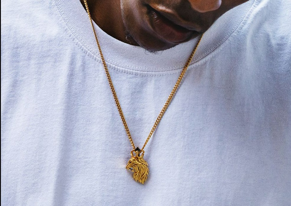 Gold lion pendant worn on chain against white shirt