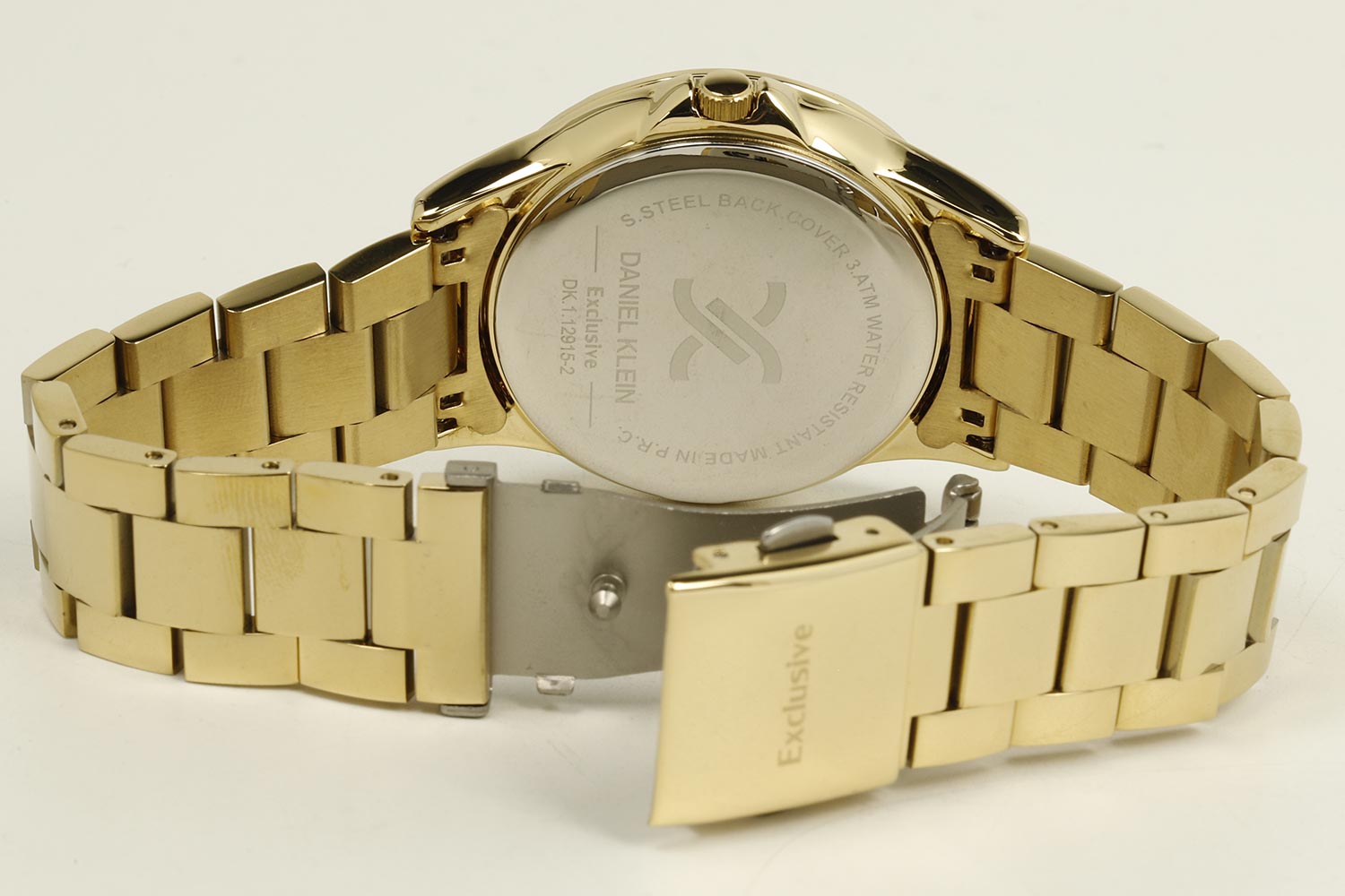 Gold watch caseback showing stainless steel back plate and fold-over clasp