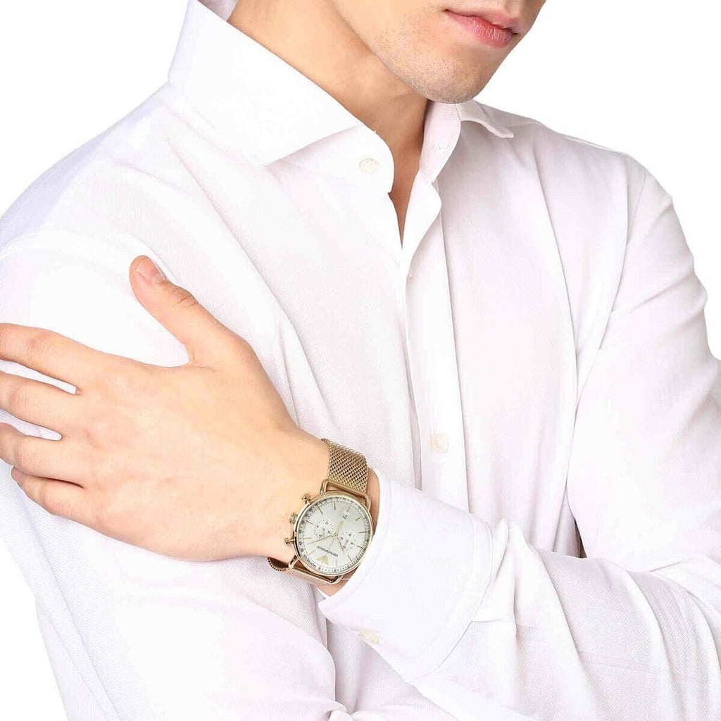 Gold chronograph watch with cream dial worn on wrist over white shirt