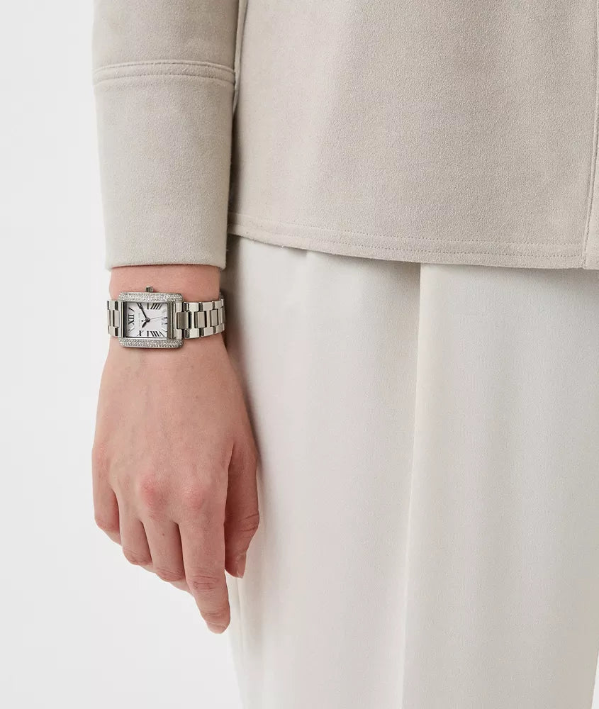 Michael Kors Emery watch worn on wrist, showing rectangular silver-tone case with crystal-studded design