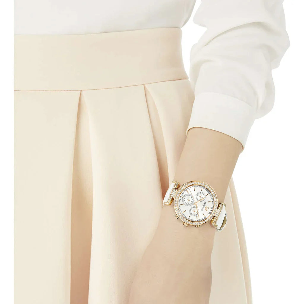 Swarovski Era Journey chronograph watch worn on wrist with white leather strap against cream-colored clothing