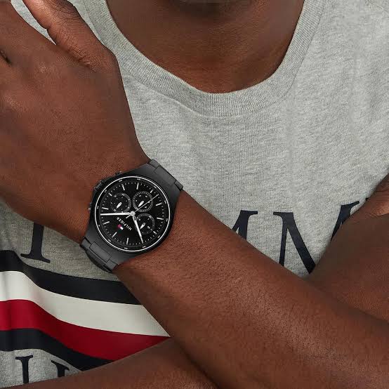 Tommy Hilfiger Justin black chronograph watch worn on wrist with gray and navy shirt