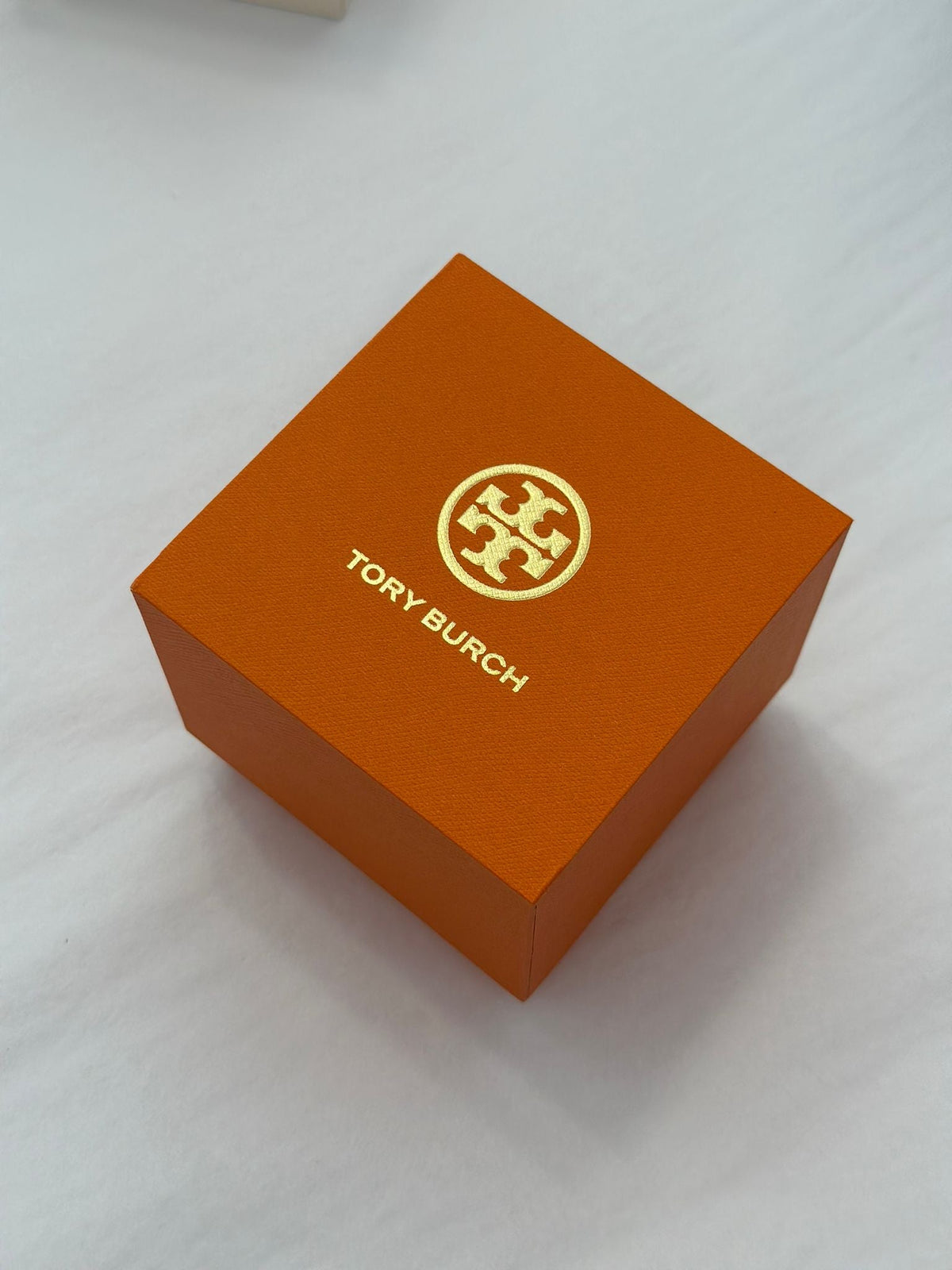 Tory Burch Classic T watch packaging with orange box and gold logo emblem