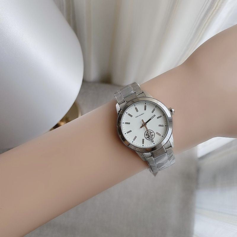 Tory Burch Collins silver watch displayed on woman's wrist with white sleeve
